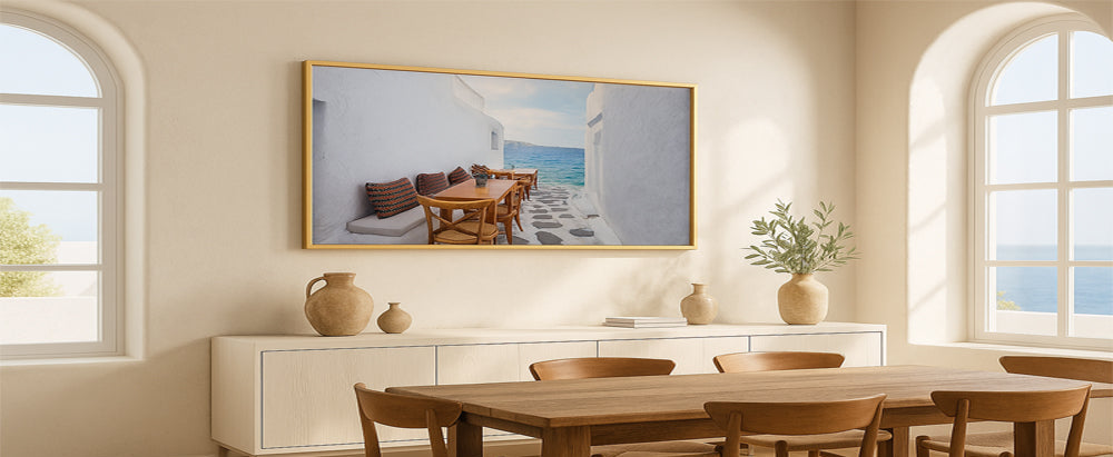 Dining room with wooden table and chairs, framed artwork on the wall, and large windows.